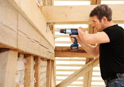 Man drilling into a wooden beam.