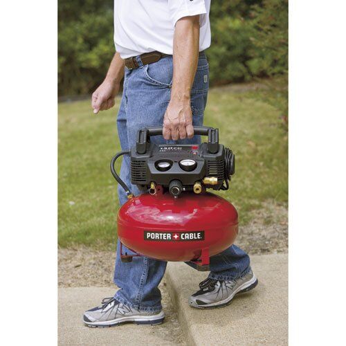 man carrying a small air compressor