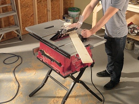 Man cutting a floor board with a portable table saw.